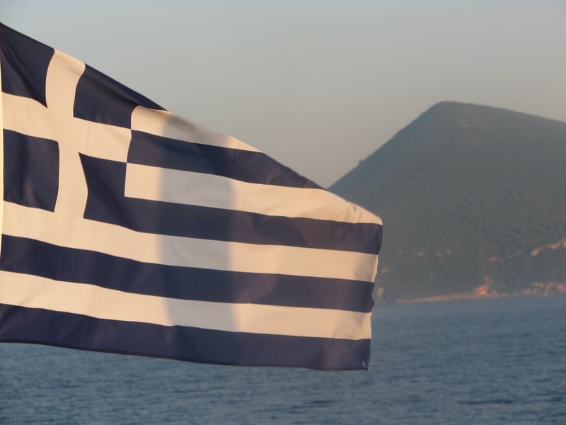 Dovolená u moře 2024 Řecko. Řecká vlajka vlaje na lodích - znamení, že dovolenou trávíte v Řecku.